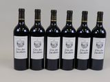 six bottles of red wine lined up in a row on a table