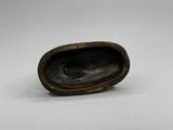 un gros plan d'un petit objet en bronze posé sur une surface blanche