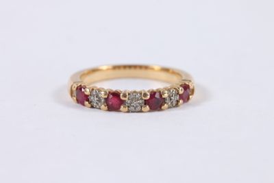 un gros plan sur une bague en or jaune sertie de pierres rouges et blanches