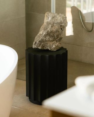 une pierre posée sur un socle dans une salle de bains, à côté d'une baignoire