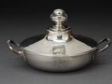 une cocotte en argent avec un couvercle posée sur une table
