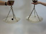 two hands holding a pair of glass bowls with chains