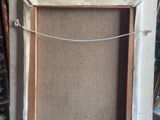 painting on easel in front of bookshelf in room with carpet