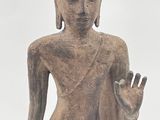 statue of a standing buddha with a raised hand in front of a cloudy sky
