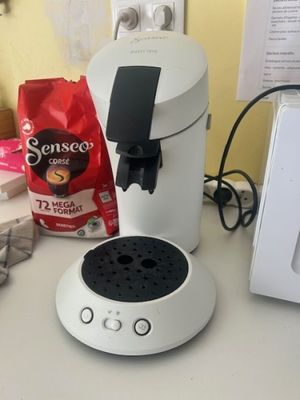 a white coffee maker sitting on a counter next to a microwave