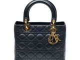 un sac à main noir muni d'une poignée dorée et de deux anses