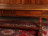a large wooden table with a red rug on the floor