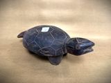 an image of a turtle figurine sitting on top of a leather surface