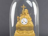 une horloge en or sous un dôme de verre sur une table