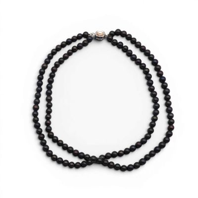 un gros plan d'un collier de perles noires sur fond blanc