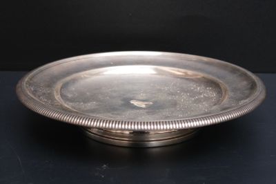 une assiette en argent posée sur une table noire, sur fond noir