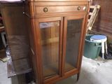 a wooden cabinet with a glass door in the middle of a room
