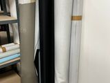 several rolls of black and white fabric sitting on top of a shelf