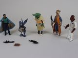 cinq figurines représentant différents personnages posées sur une surface blanche