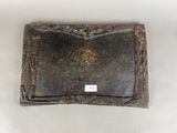an old leather wallet with a tag on it sitting on a white surface