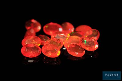 some red glass beads are sitting on a black surface