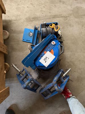 un homme debout à côté d'une pince et d'une machine bleue