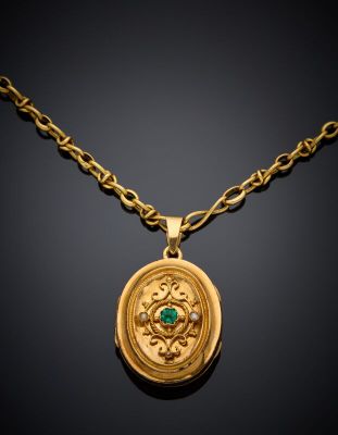 a gold necklace with a green stone in the center