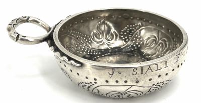 a silver bowl with a handle on a white surface