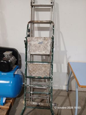 une échelle appuyée contre un mur, à côté d'un compresseur d'air bleu
