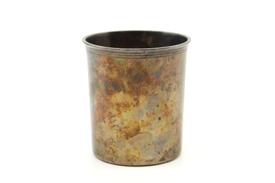 une tasse en métal posée sur une surface blanche