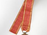 an old medal with a ribbon around it on a white surface
