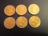 quatre pièces d'or ornées d'un blason, posées sur un fond noir