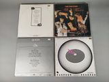 three cd ' s are sitting on a table, one is a record