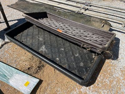 une grille métallique posée par terre à côté d'un bac en plastique