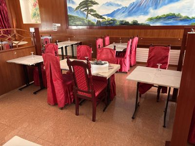 des tables et des chaises dans un restaurant où est accroché un grand tableau au mur