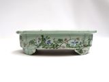 green and white ceramic planter with flowers on it on a white surface