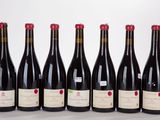 six bouteilles de vin sont alignées sur une surface blanche