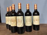 six bottles of wine are lined up on a wooden table