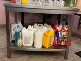 une table en métal sur laquelle se trouvent plusieurs bouteilles de produits d'entretien