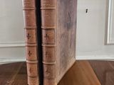 two old books sitting on a wooden table in a room