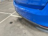 a blue car parked in a parking lot next to a building