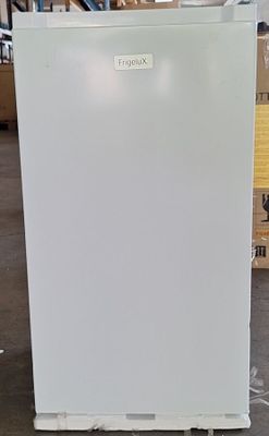 un réfrigérateur blanc dans un entrepôt, avec des cartons en arrière-plan