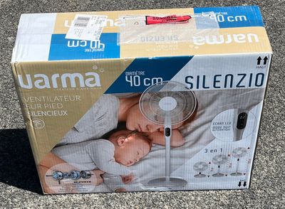 une boîte posée par terre, contenant un ventilateur