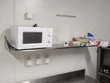 an image of a kitchen with a microwave on a shelf