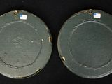 two green plates sitting on top of a black table next to each other