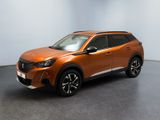 Le SUV orange est garé dans une pièce aux murs blancs.