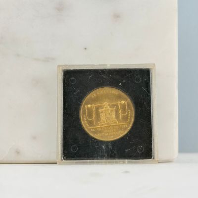 une pièce d'or posée sur un bloc de marbre
