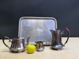 a silver tea set with a tray and a lemon on the table