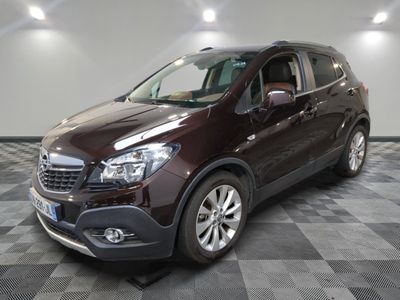 Le SUV Buick marron est garé sur un sol en carrelage à damier.