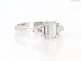 a close up view of a three stone engagement ring with a baguet cut diamond