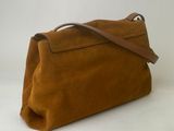 a brown sued handbag with a leather strap on a white background