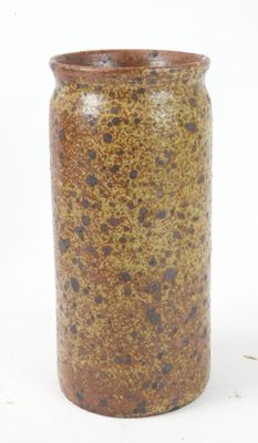 a brown and black vase sitting on a white surface