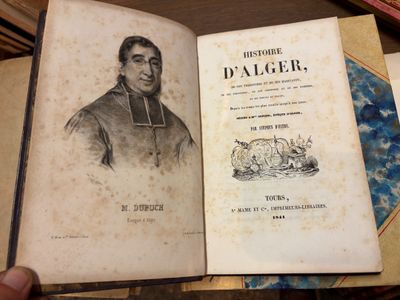 une personne tenant un livre sur lequel figure la photo d'un homme