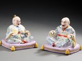 paire de figurines en porcelaine représentant un homme et une femme assis sur un coussin violet