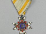 une médaille d'argent entourée d'un ruban jaune et blanc